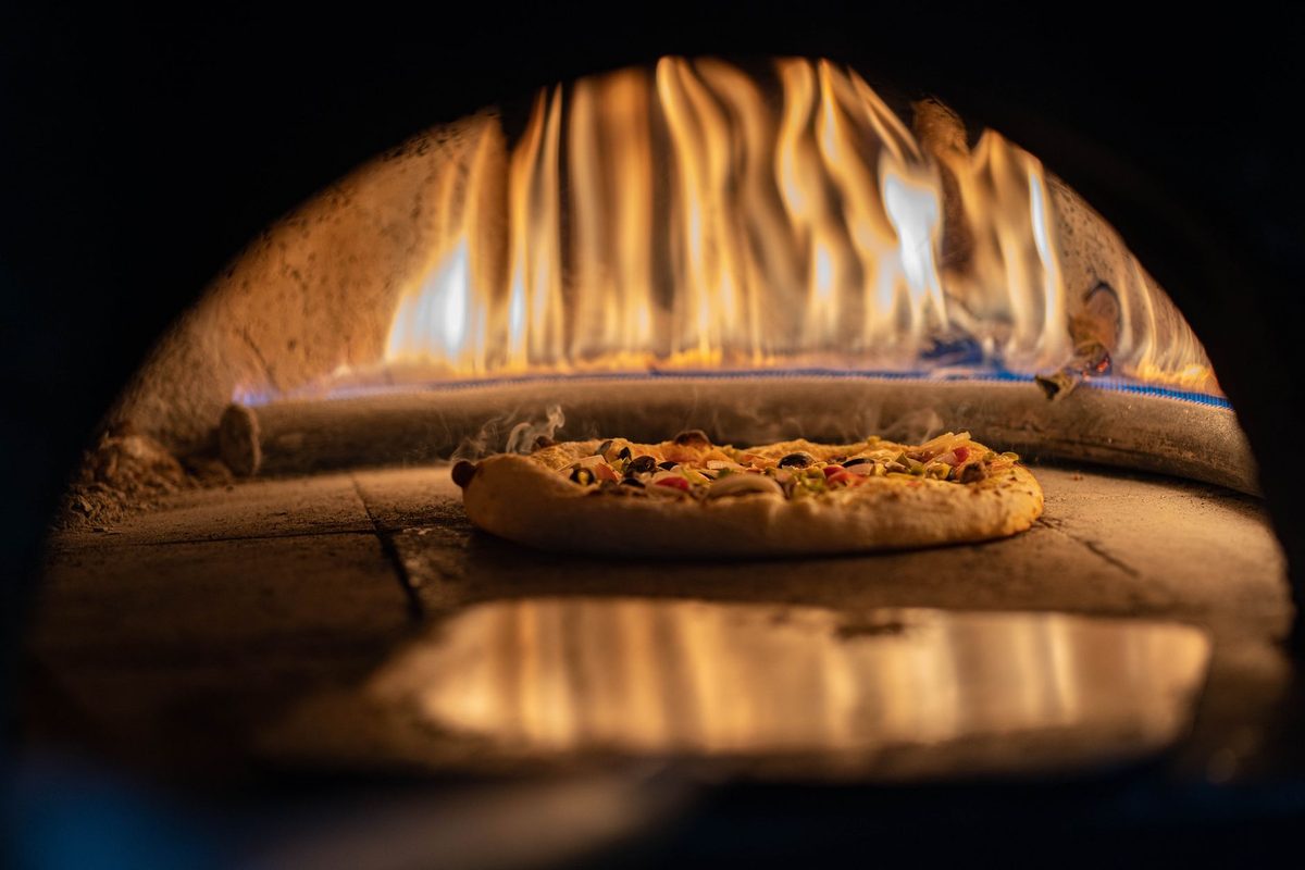 Professional restaurant kitchen with authentic wood-fired oven and separate preparation areas for allergen safety